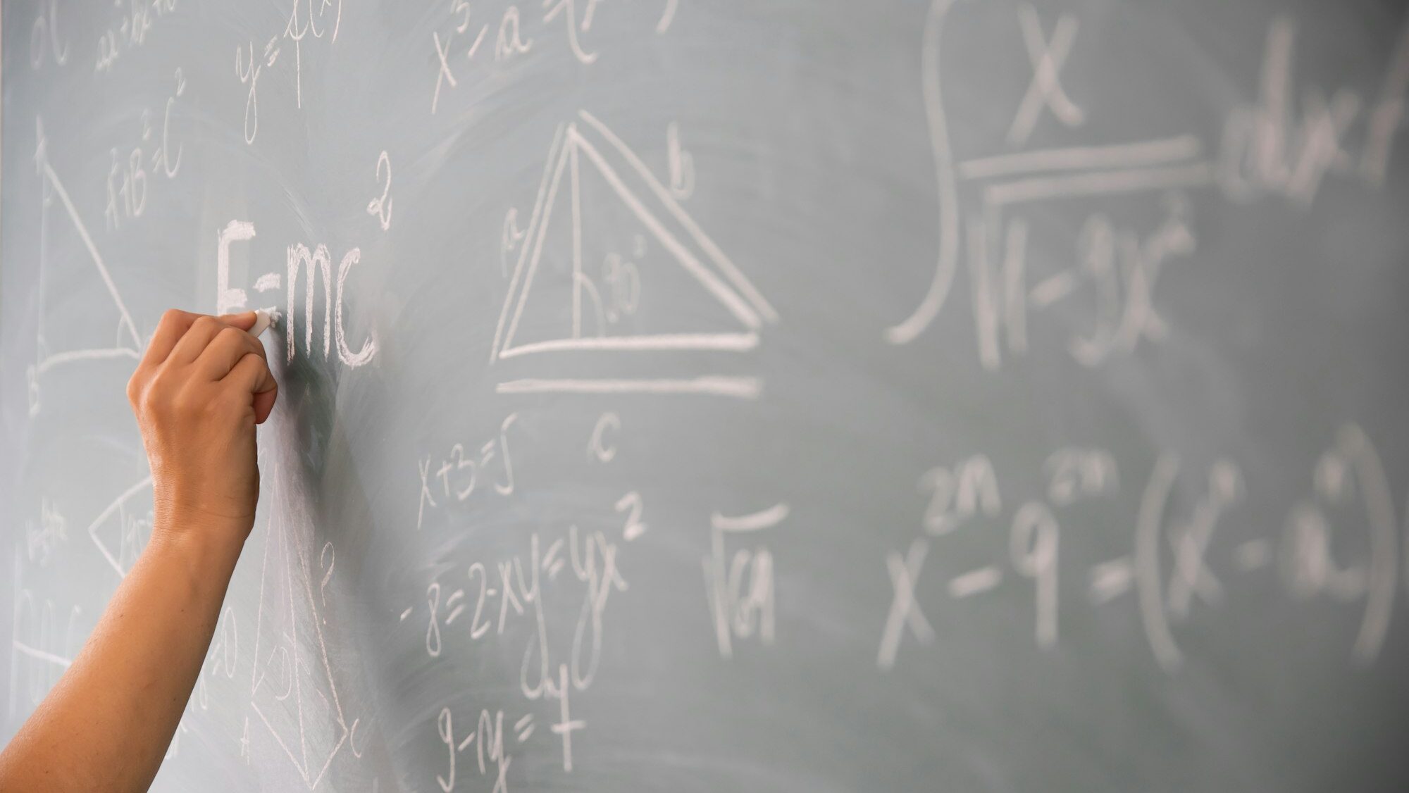 Teacher or student writing on blackboard during math lesson in school classroom